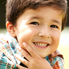 A young boy with his hand around his chin, smiling