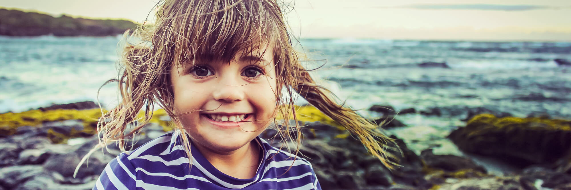 A young girl smiling with her hair blowing in the wind