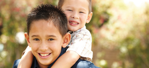 Two children, presumably brothers. The smaller one draped on the larger one's shoulders.