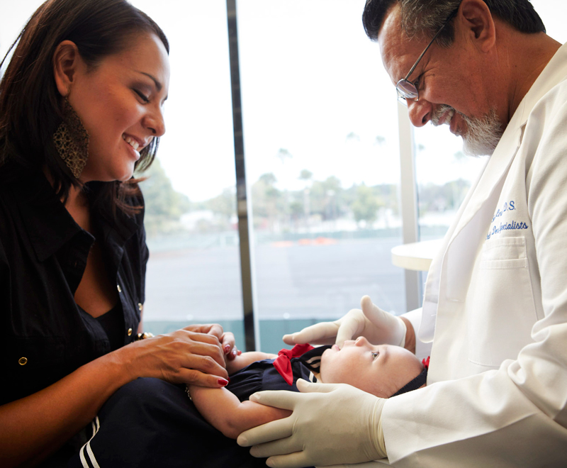 Dr. Cortez treating a baby with the baby's mother watching and smiling