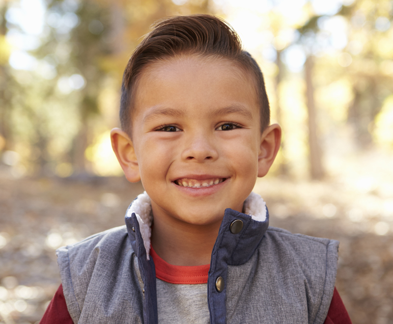 A young boy in the woods, smiling