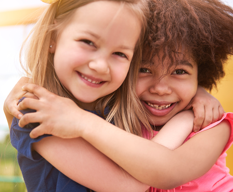 Two young girls hugging and smiling